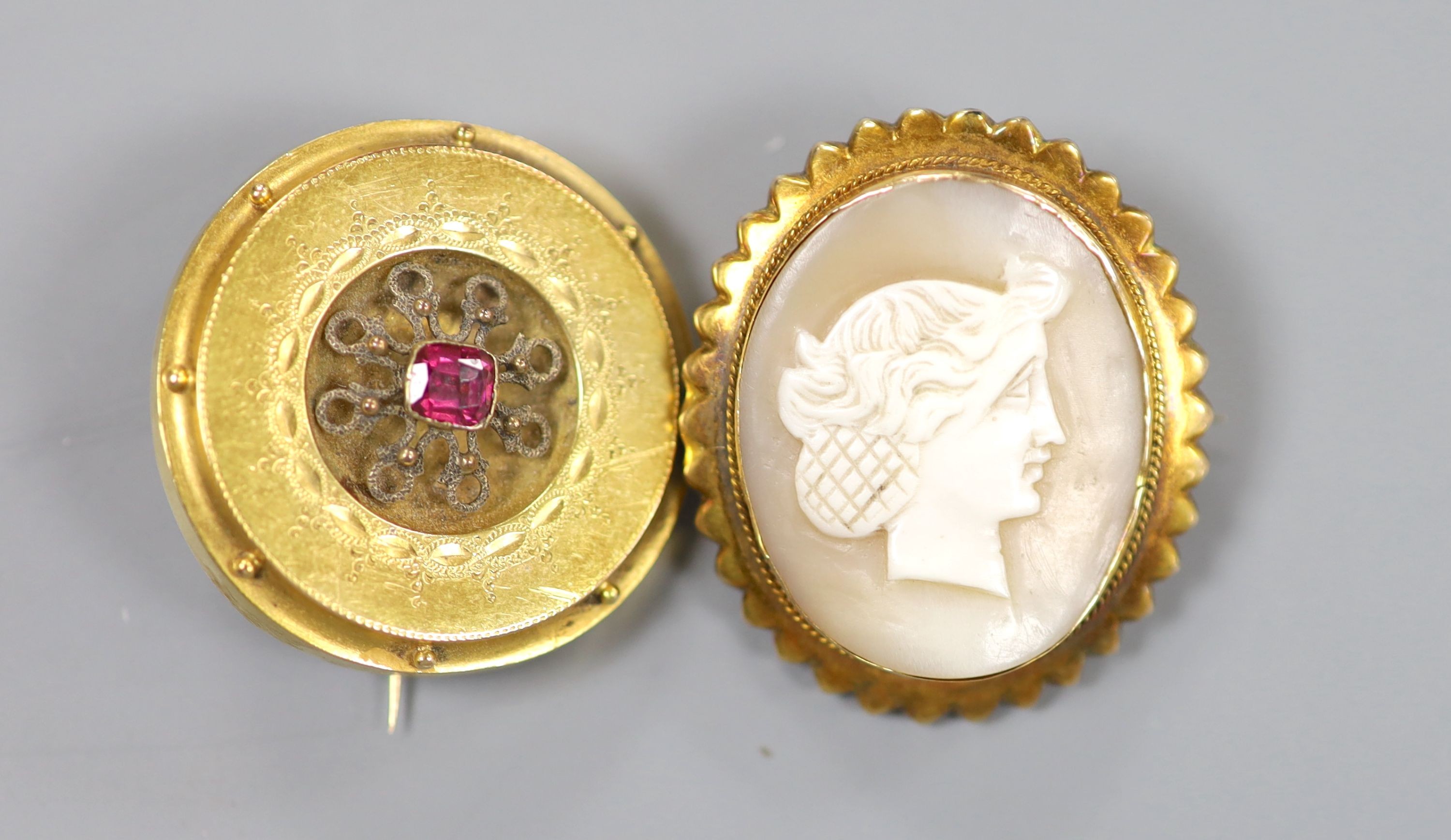 An early 20th century 9ct mounted oval cameo shell brooch, 36mm and an earlier yellow metal and gem set circul17.6 grams.ar brooch, 32mm, gross weight